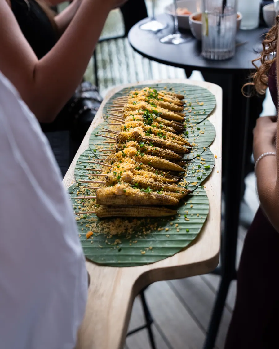 Gegrilde babymaïs met kaas en bieslook op een bananenblad